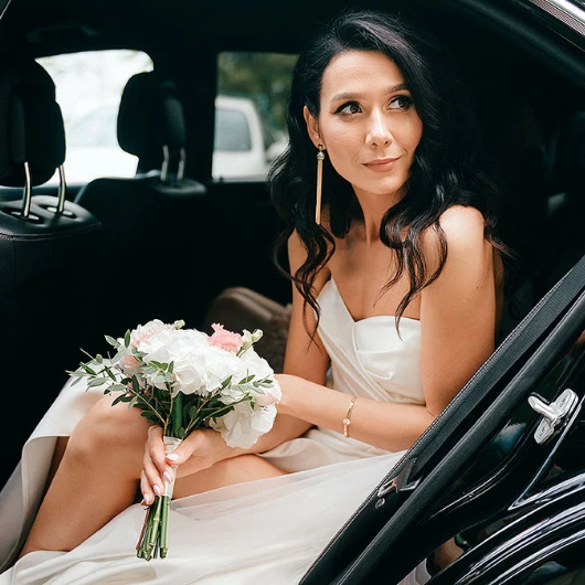A bride in a white dress sitting in a luxury fleet